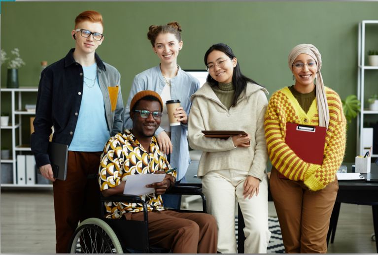 9 people around a table touching hands in the centre, inclusion together